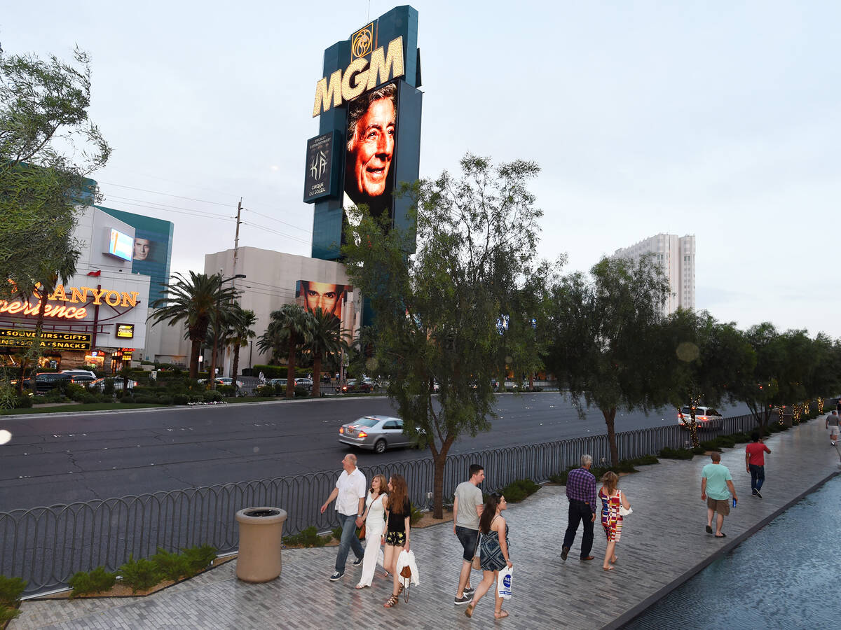 Pedestrians walk down the Strip as the MGM Grand marquee displays an image of Tony Bennett duri ...