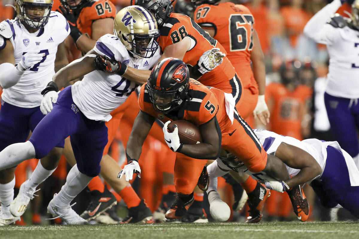 Oregon State running back Deshaun Fenwick (5) is brought down by Washington's Edefuan Ulofoshio ...