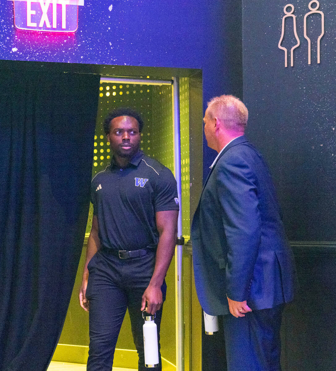 Washington Huskies head coach Kalen DeBoer, right, leaves the podium as linebacker Edefuan Ulof ...