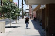 A visitor braves the hot weather with an umbrella and ice cold drink on Las Vegas Boulevard at ...