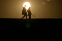 FILE - People walk along a trail as the sun sets, Sunday, July 16, 2023, in Death Valley Nation ...