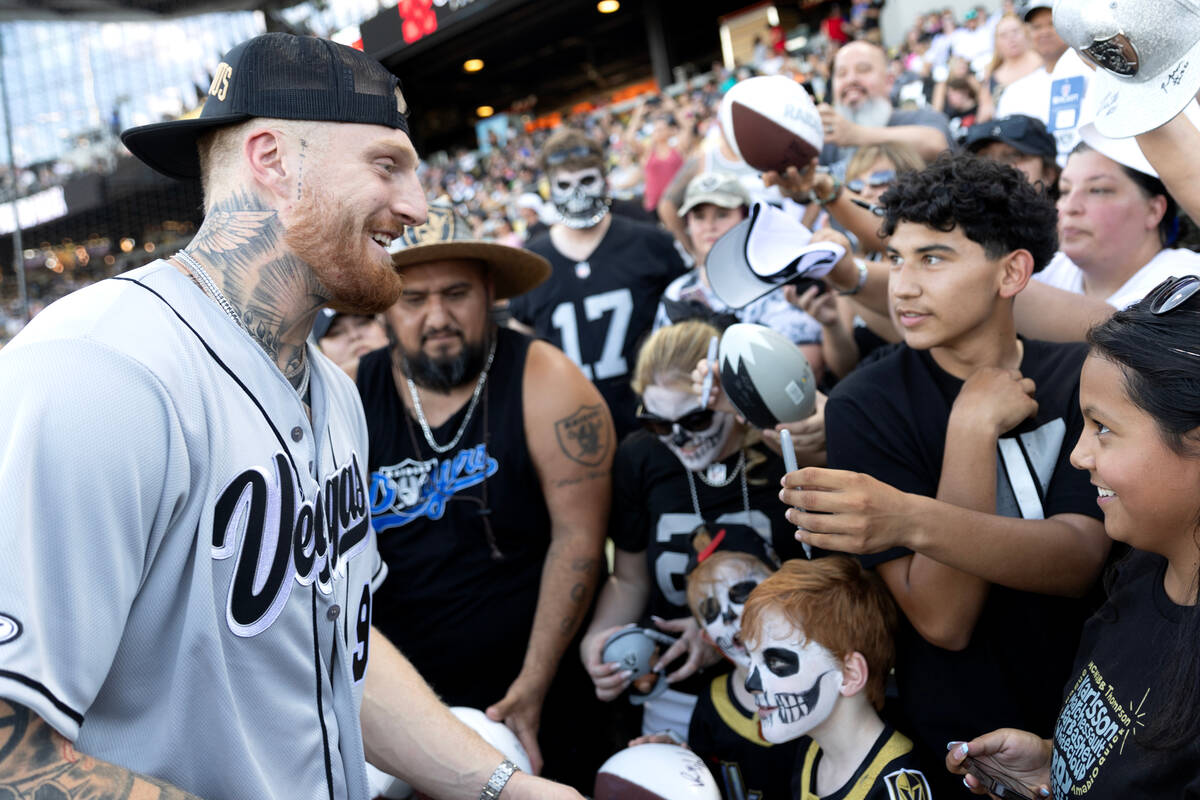 Raiders defensive end Maxx Crosby signs autographs for fans before the annual Battle for Vegas ...