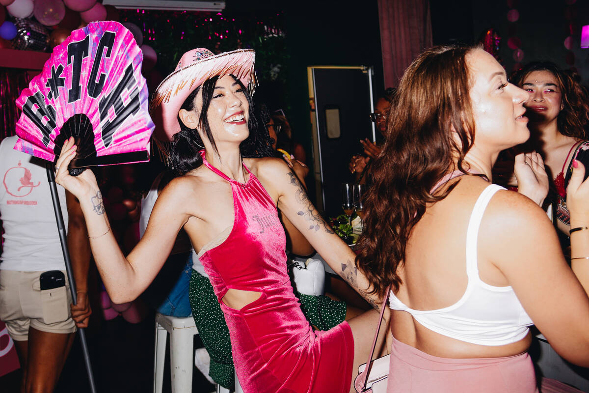 A woman wears a pink cowgirl hat and uses a fan during a Barbie themed drag show brunch on Sund ...