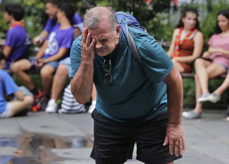 Russ Wilson splashes water on his face from a fountain in New York, Wednesday, July 17, 2019. T ...