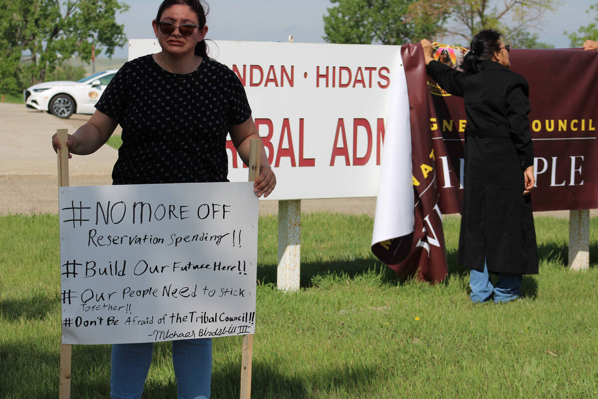A woman holds a sign at a protest outside MHA Nation tribal headquarters in New Town, North Dakota.