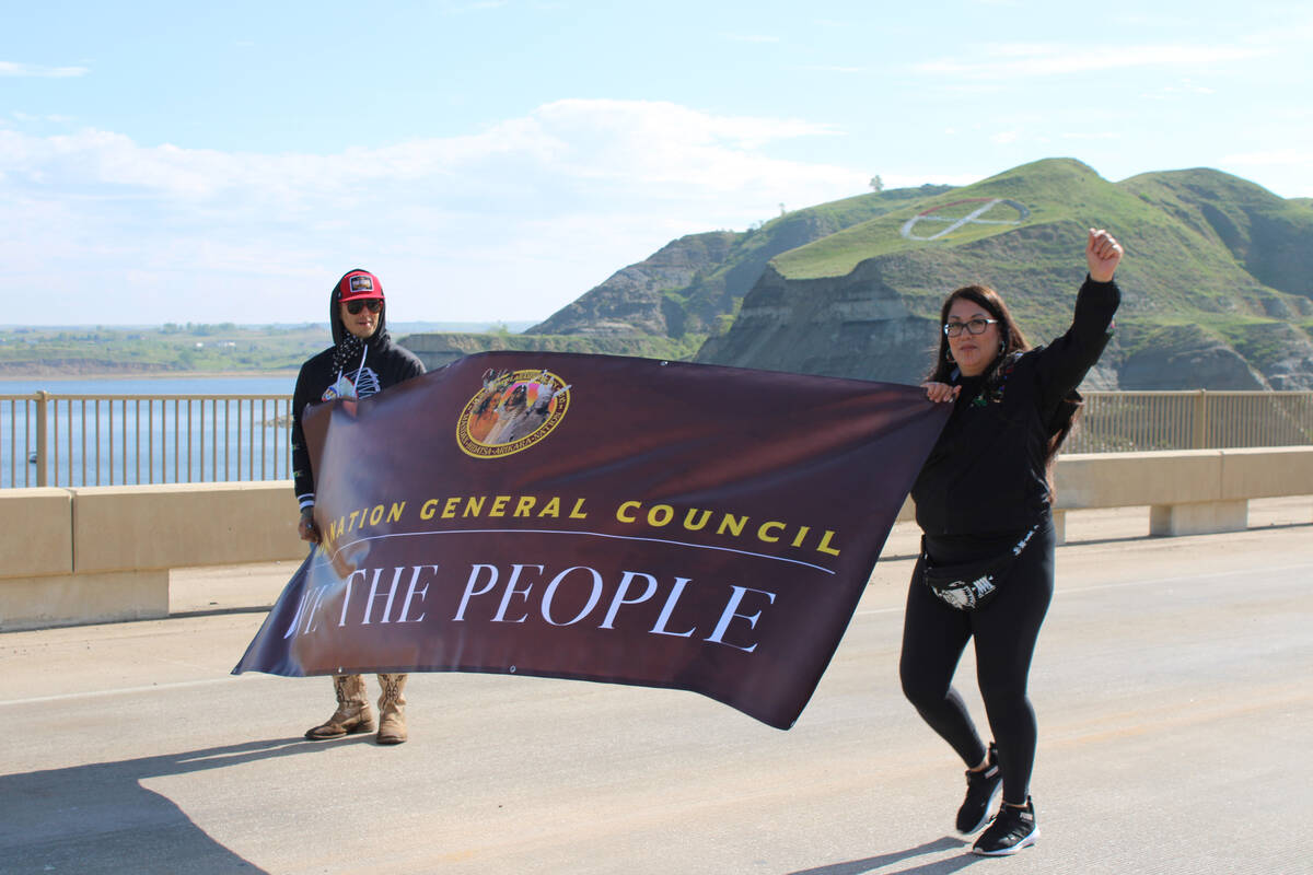 Kelly Hosie, right, holds a banner with another protester in New Town, North Dakota.