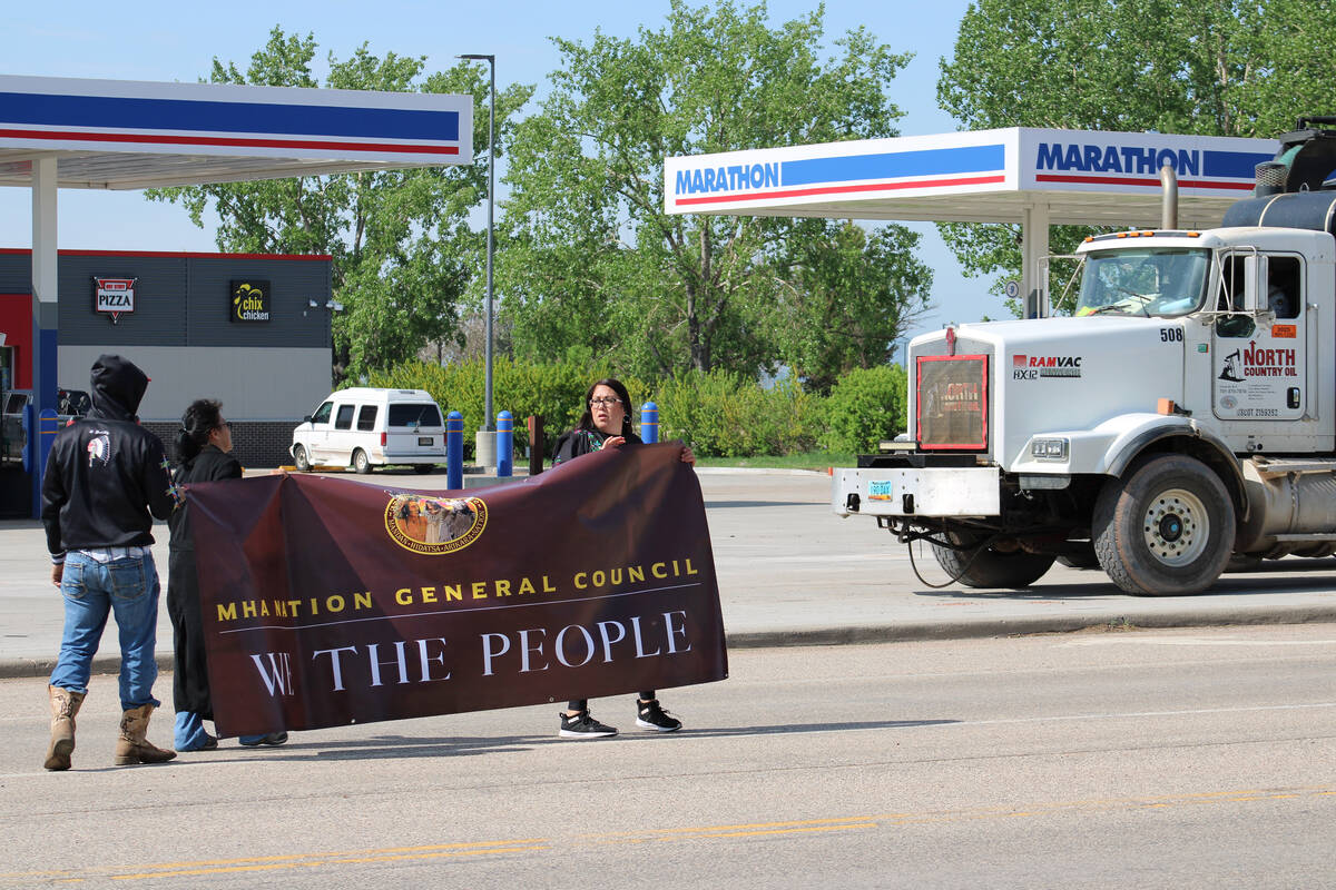 Kelly Hosie, right, holds a banner with other protestors in New Town, North Dakota.
