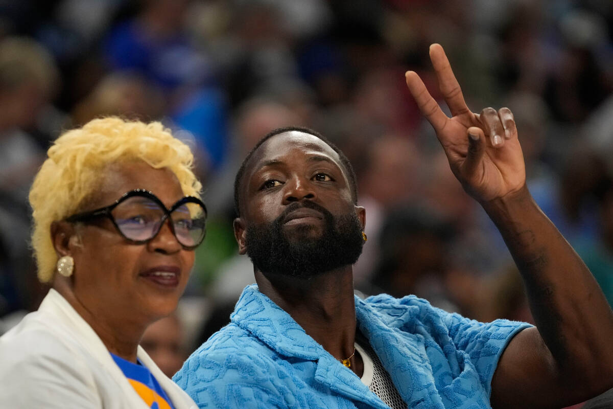 Former NBA player Dwayne Wade flashes a peace sign during the second half of a WNBA basketball ...
