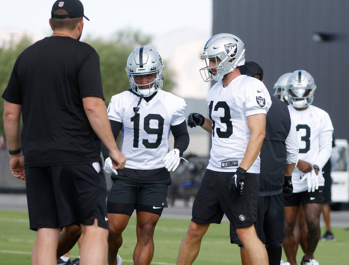 Raiders wide receivers Hunter Renfrow (13) and DJ Turner (19) listen to their coach during trai ...