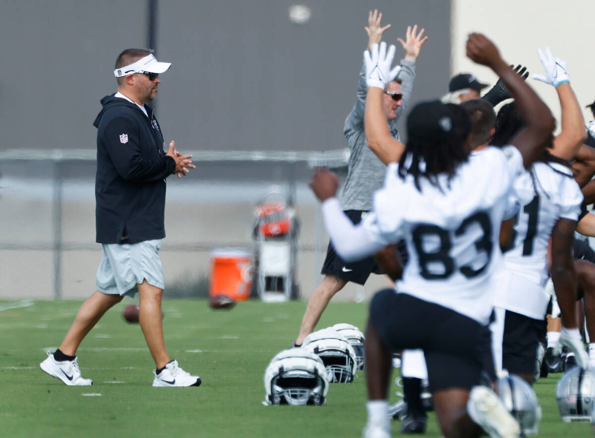 Raiders head coach Josh McDaniels watches as his players stretch during training camp at the In ...