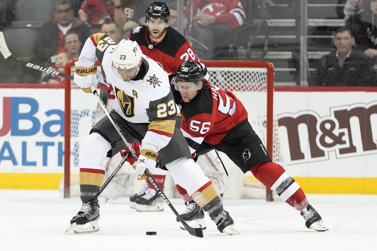 Vegas Golden Knights defenseman Alec Martinez (23) fights for the puck against New Jersey Devil ...