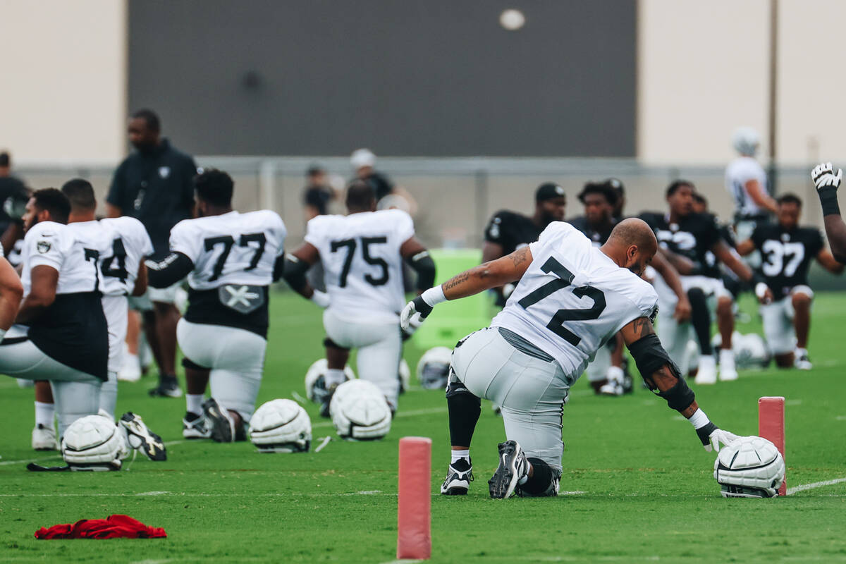 Raiders offensive tackle Jermaine Eluemunor (72) grabs his helmet during training camp warmups ...