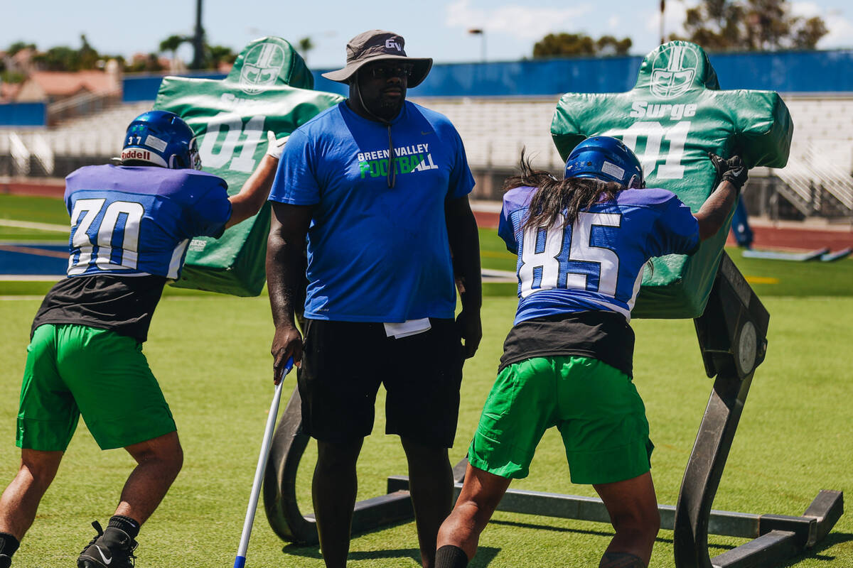 Green Valley defensive line coach Brian Bell, middle, runs through drills with his players duri ...