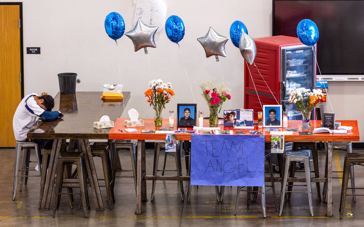 A mourner lays his head down on a memorial table of items from Angel Naranjo during a food and ...