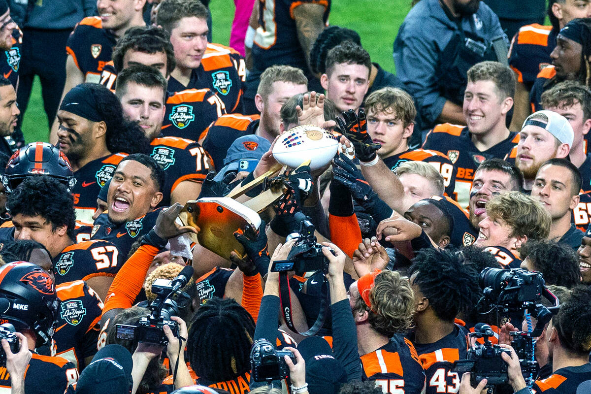 Oregon State Beavers players touch and pass along the Rossi Ralenkotter trophy after defeating ...