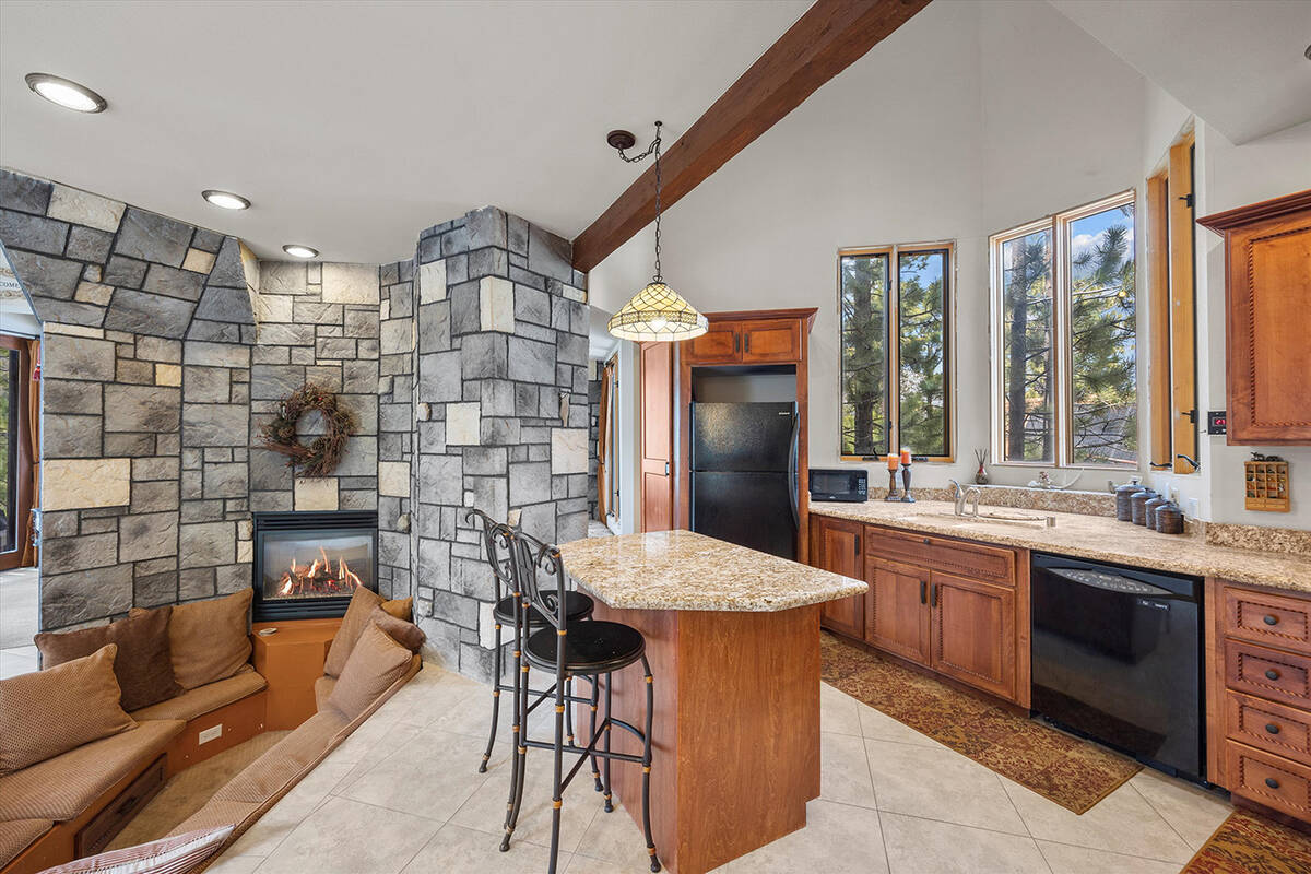 The stylish kitchen boasts a central island with granite countertops, custom cabinetry and blac ...