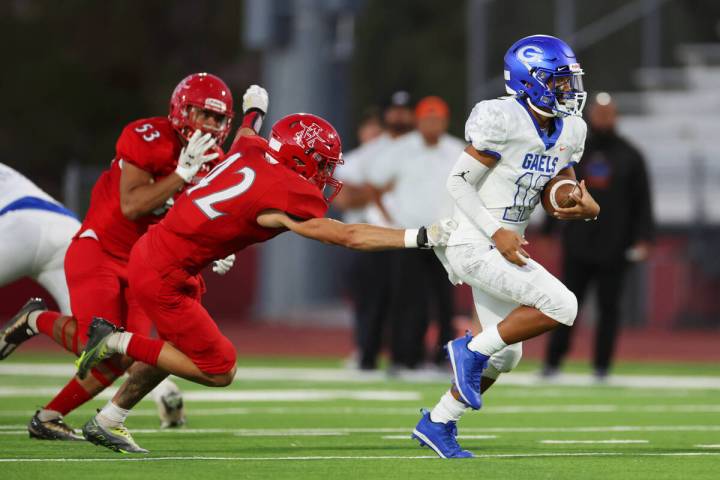 Bishop Gorman's Micah Alejado (12) runs the ball under pressure from Arbor View's Amari Derby C ...