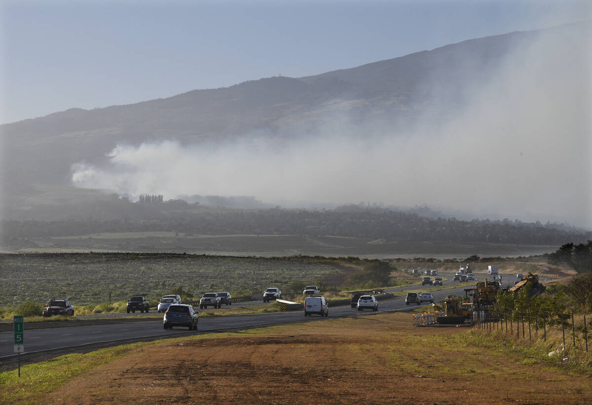 Smoke blows across the slope of Haleakala volcano on Maui, Hawaii, as a fire burns in Maui's up ...