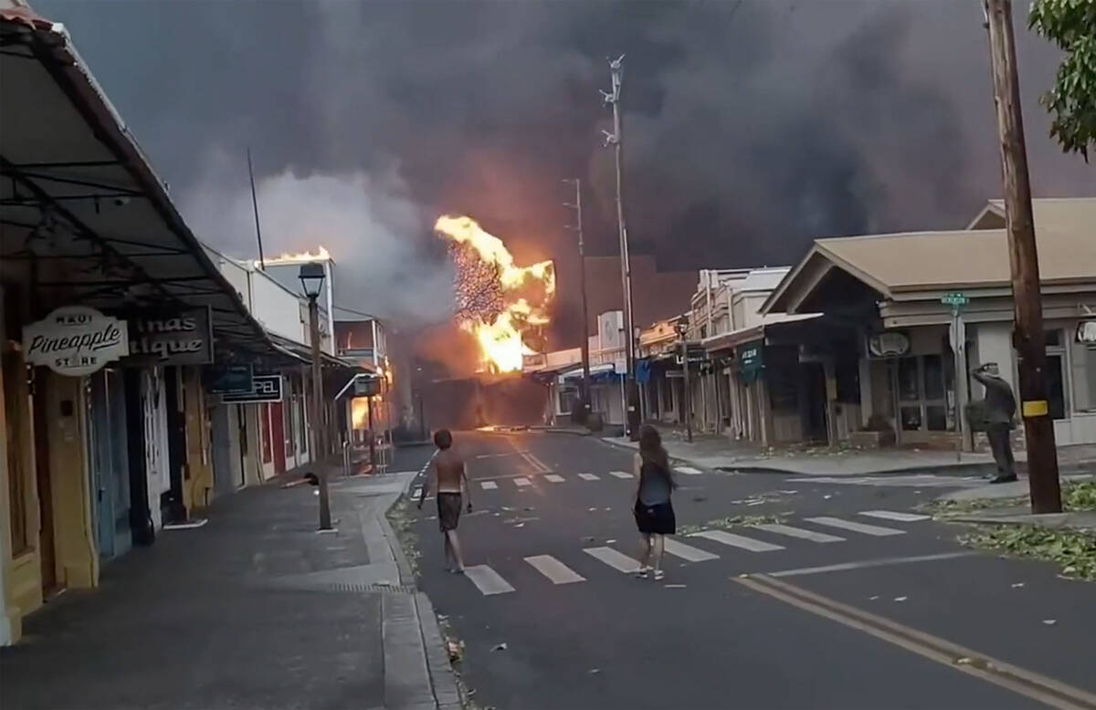 People watch as smoke and flames fill the air from raging wildfires on Front Street in downtown ...