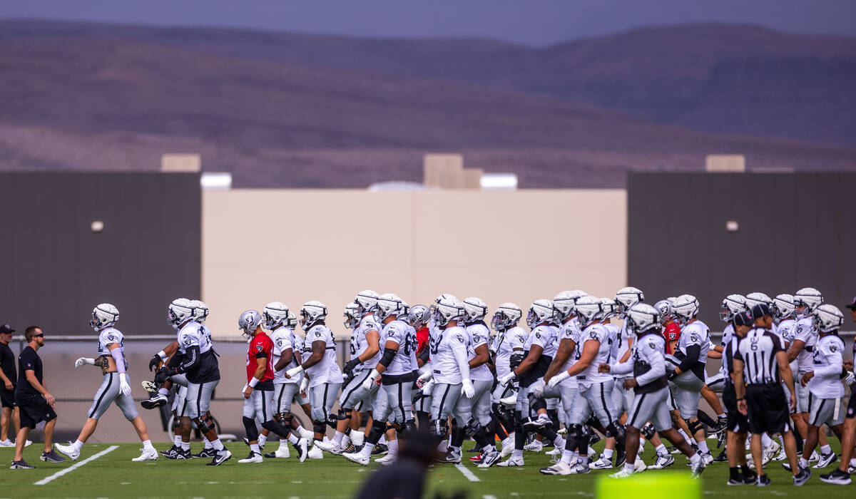 Raiders defensive end Maxx Crosby (98), left, leads his team for warmups during training camp a ...