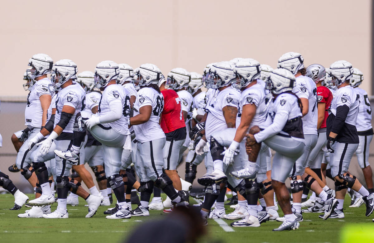 Raiders center Andre James (68), left, lifts his leg for warmups during training camp at the In ...