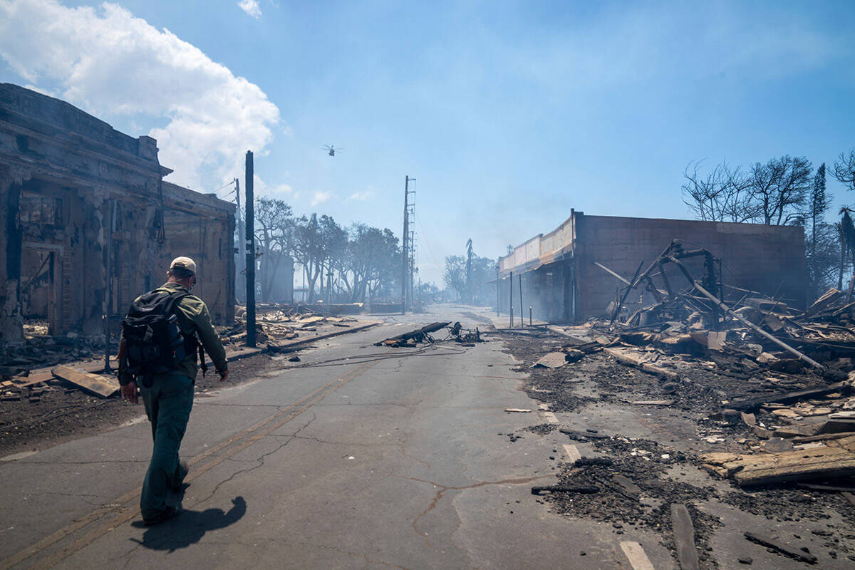 In this photo provided by Tiffany Kidder Winn, a man walks past wildfire wreckage on Wednesday, ...