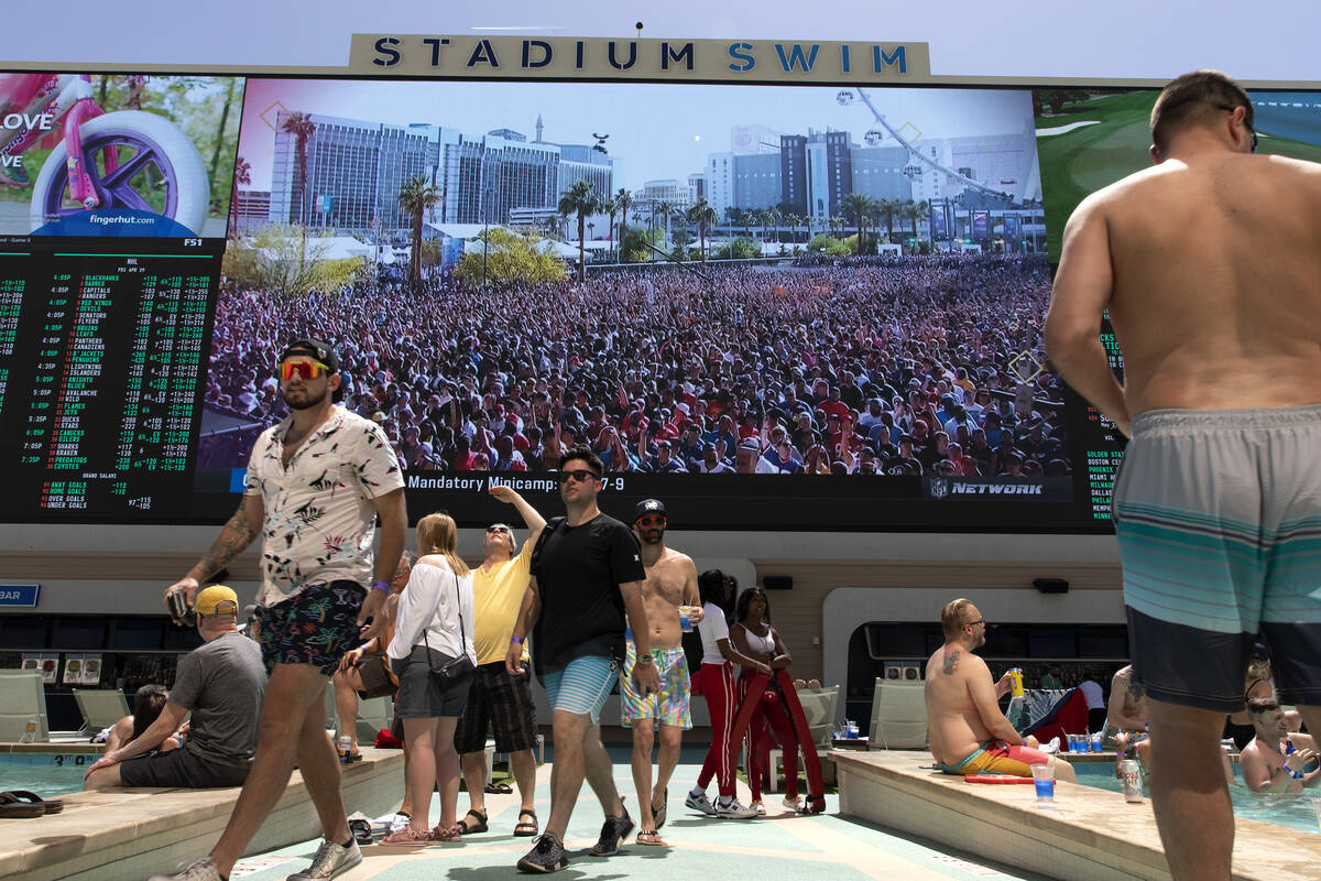 The crowd at the NFL draft on the Las Vegas Strip is seen on the screen at Stadium Swim as pool ...