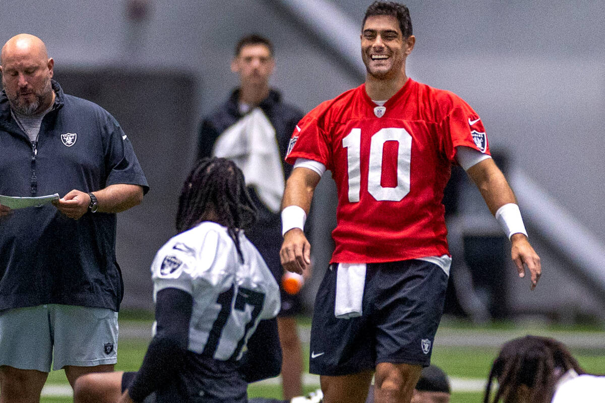 Raiders quarterback Jimmy Garoppolo (10) talks with wide receiver Davante Adams (17) during tra ...