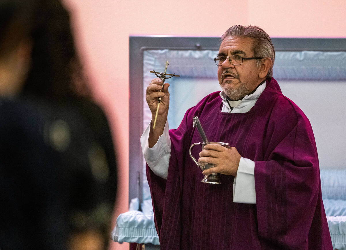 The Rev. Jorge Hernandez presents the family with a cross from the casket during funeral servic ...