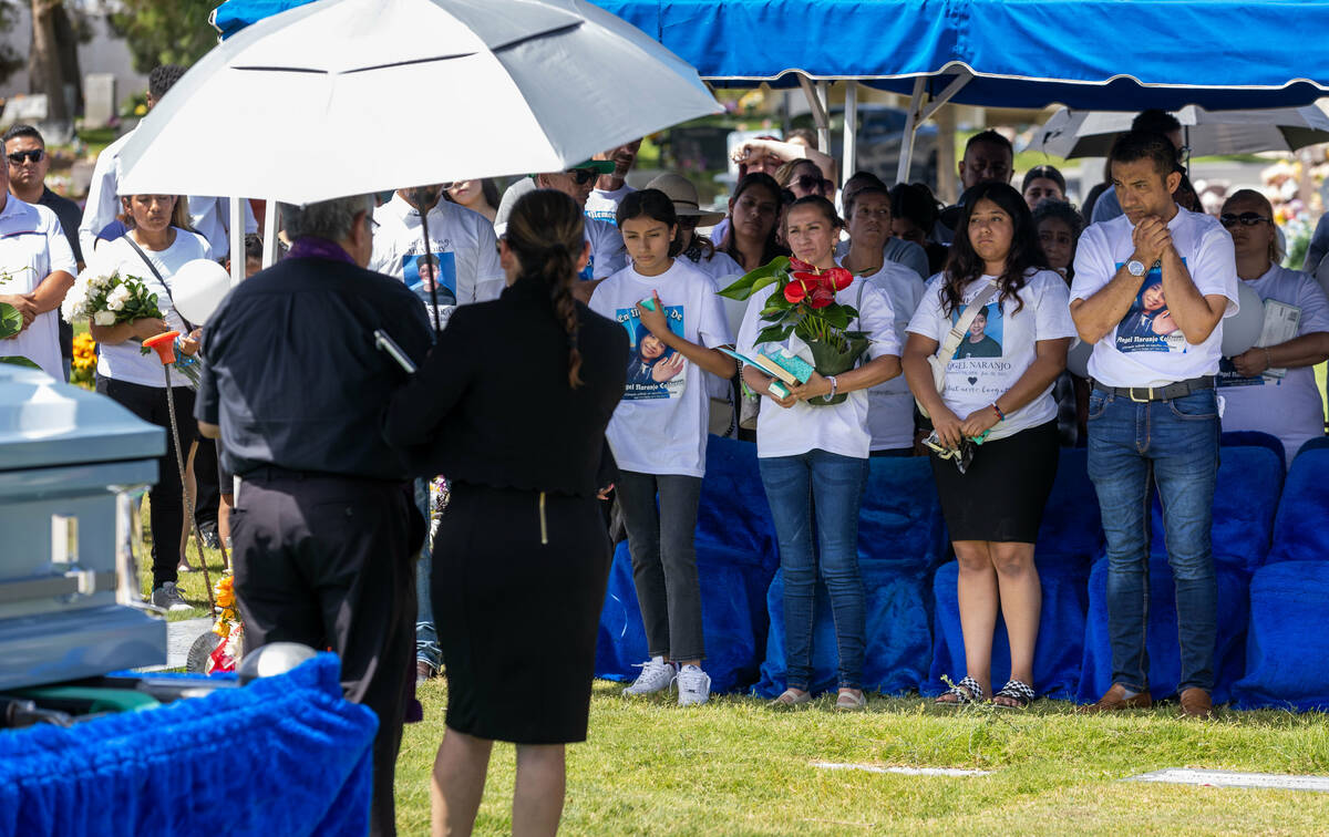 Family and friends gather to hear Rev. Jorge Hernandez give the final prayers graveside during ...