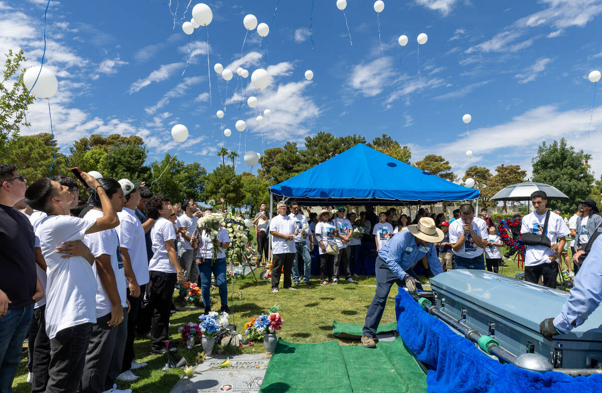 Balloons are released as the casket of Angel Naranjo is lowered into the ground during funeral ...