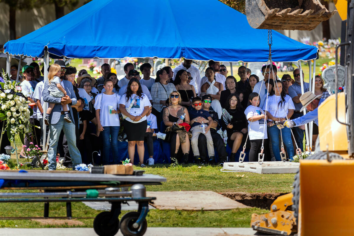 Mourners gather to watch the covering up of Angel Naranjo's casket following funeral services g ...