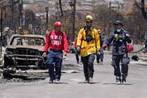 Members of a search-and-rescue team walk along a street, Saturday, Aug. 12, 2023, in Lahaina, H ...