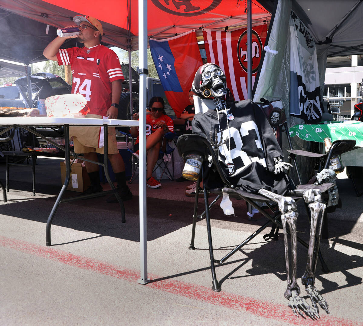 A Raiders fan skeleton chills out as a San Francisco 49ers fans drinks a beer before the first ...