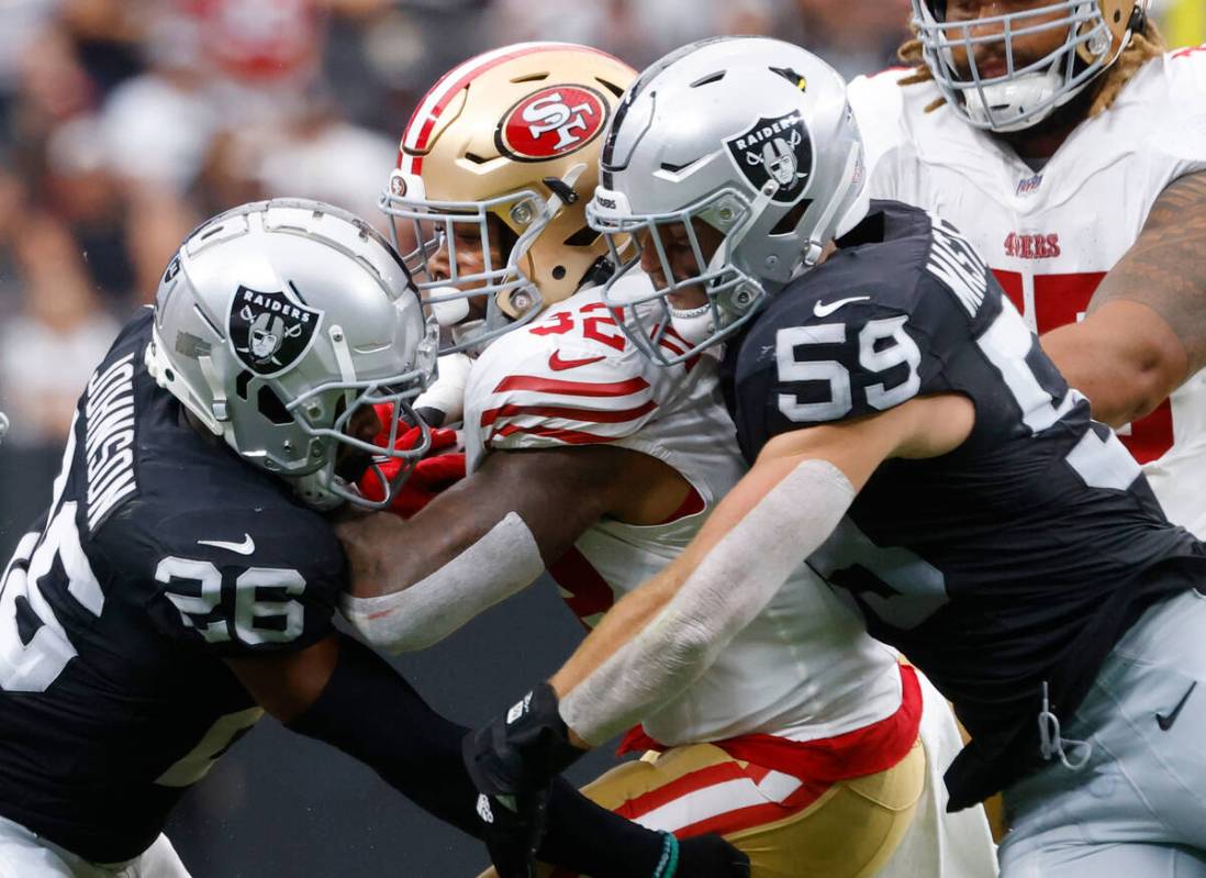 San Francisco 49ers running back Tyrion Davis-Price (32) is sandwiched between Las Vegas Raider ...