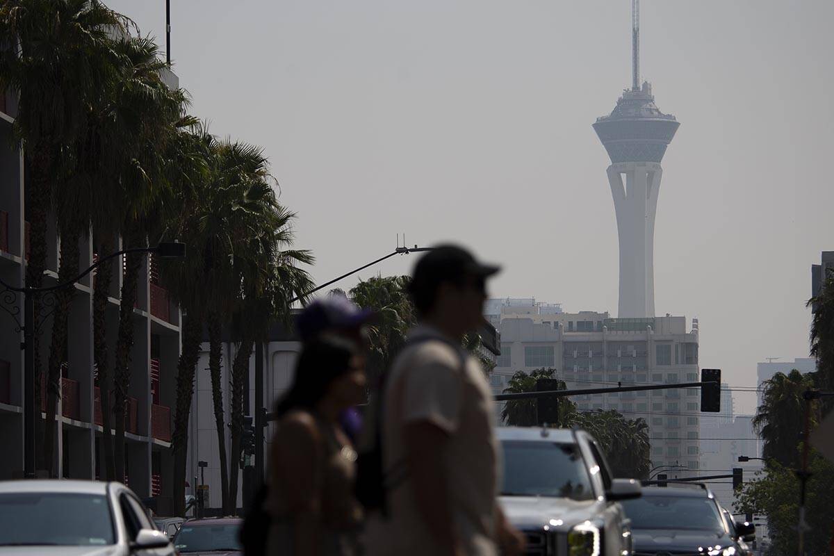 Pedestrians walk through Fremont Street Experience while smoky skies cloud the STRAT on Aug. 7, ...