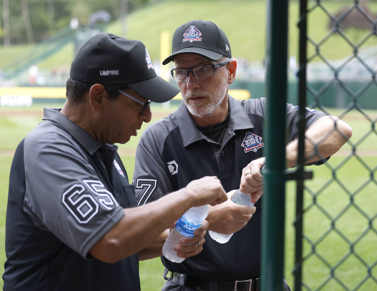 Ben Sprague of Las Vegas, right, and Andy Pagan, volunteer umpires, take water break during the ...