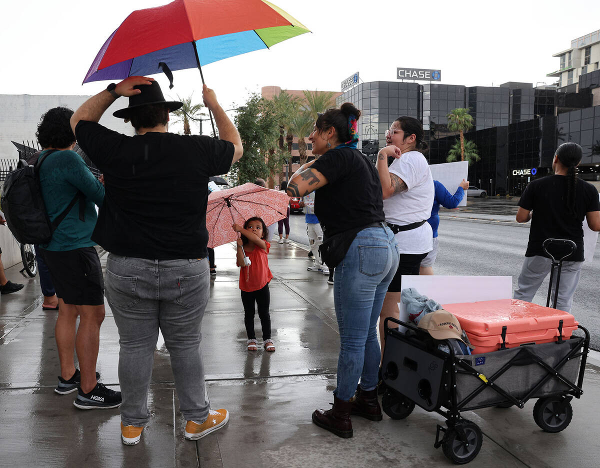 People shelter from rain on Las Vegas Boulevard in downtown Las Vegas Friday, Aug. 18, 2023. (K ...