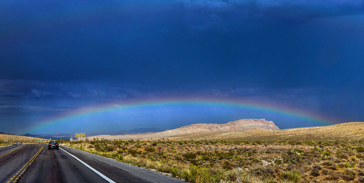 A rainbow stretches across the sky in the distance beyond the Red Rock Canyon National Conserva ...