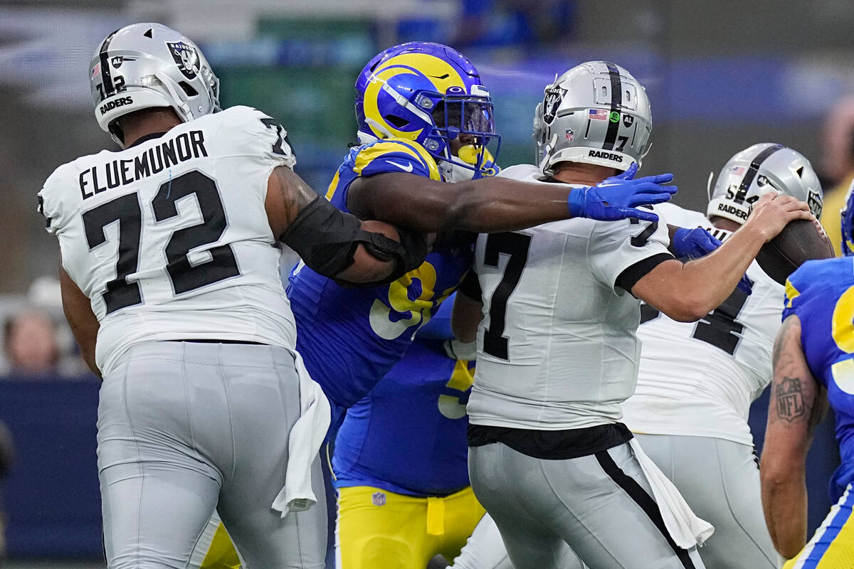 Las Vegas Raiders quarterback Brian Hoyer, right, is sacked by Los Angeles Rams linebacker Keir ...