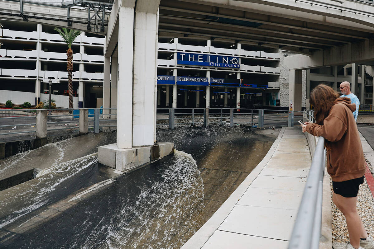People watch as water flows into a flood channel from The Linq parking garage on Sunday, Aug. 2 ...
