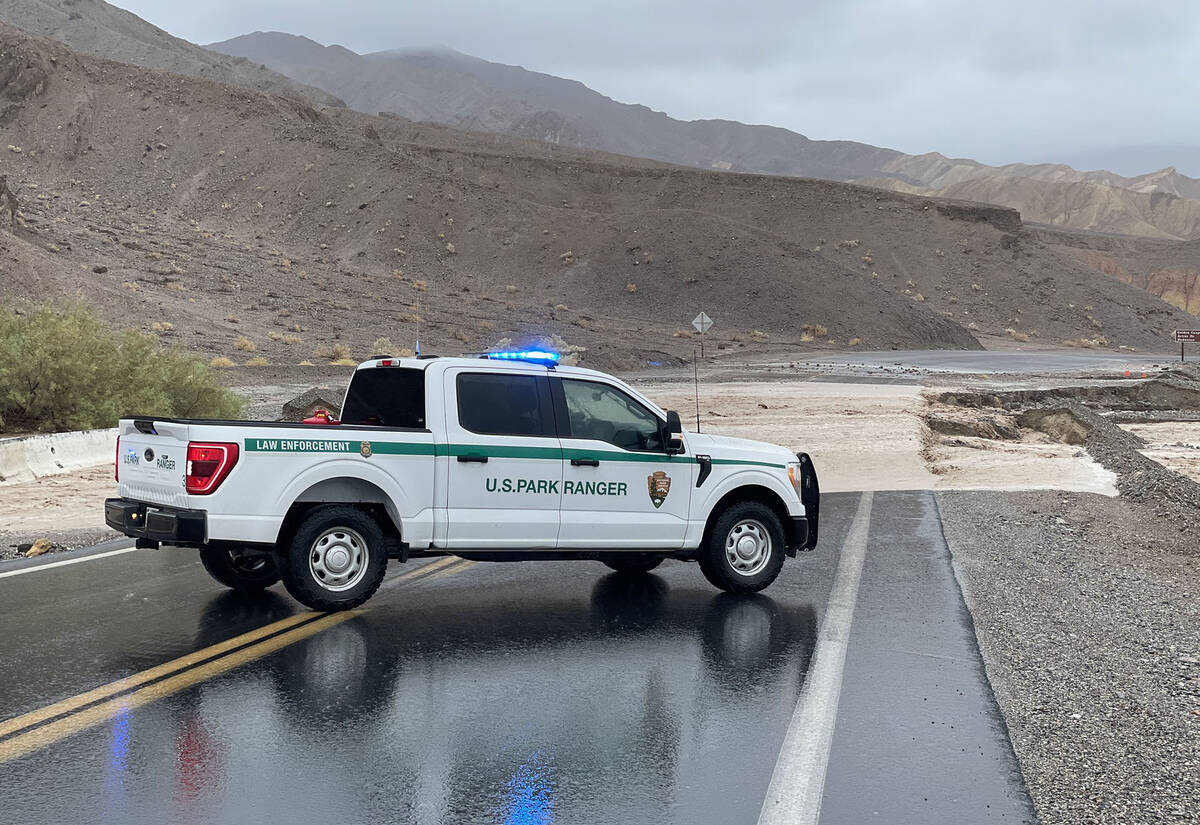 A National Park Service vehicle parked in front of active flooding on Badwater Road near the ju ...