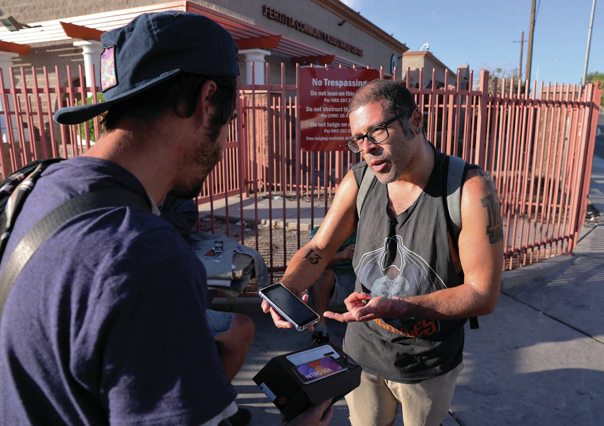 Elmer Montufar Jr., 39, gives a phone to friend Brandon Dockerty, 36, on Main Street outside th ...