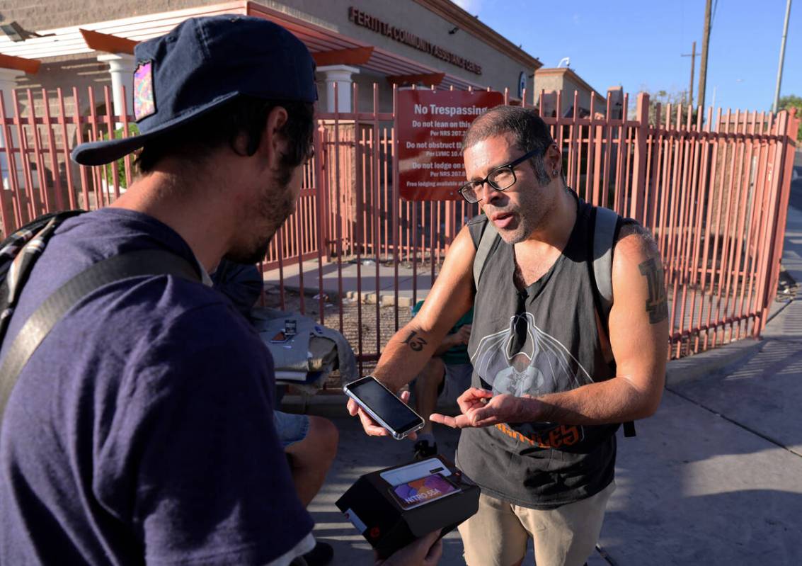 Elmer Montufar Jr., 39, gives a phone to friend Brandon Dockerty, 36, on Main Street outside th ...