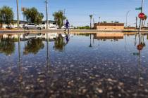 A woman walks along East Sahara Avenue where water remains pooled up near the intersection with ...