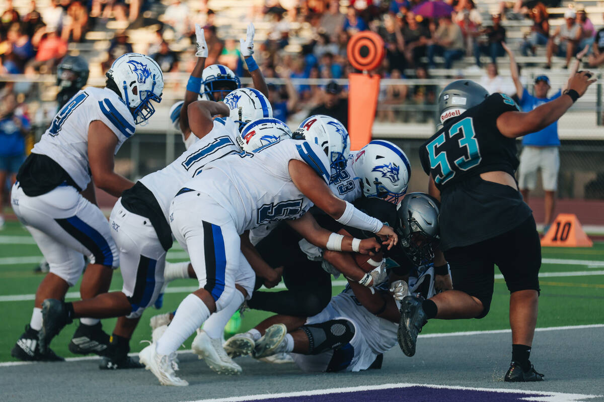 Silverado running back Kaina Crisostomo (15) gets piled on by a group of Basic players for a sa ...