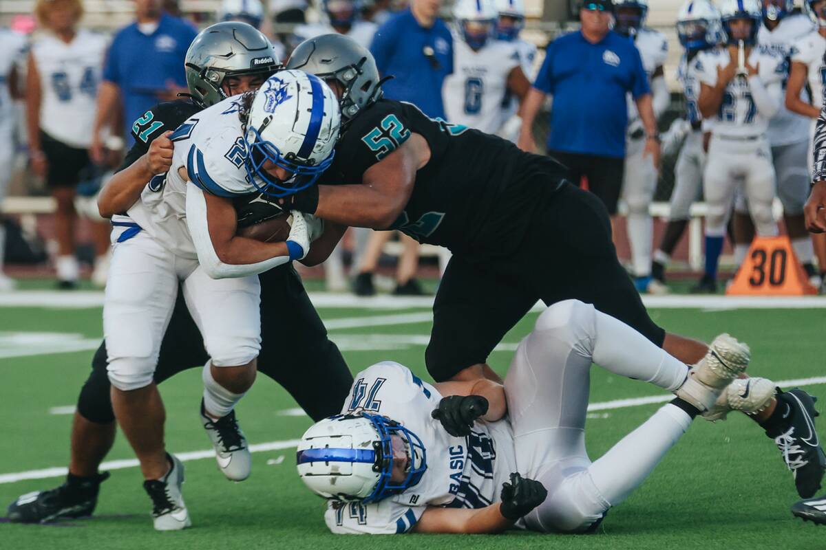 Basic running back Boston Wren (24) gets wrapped up by Silverado's Noah Mendez (21) and Jayland ...