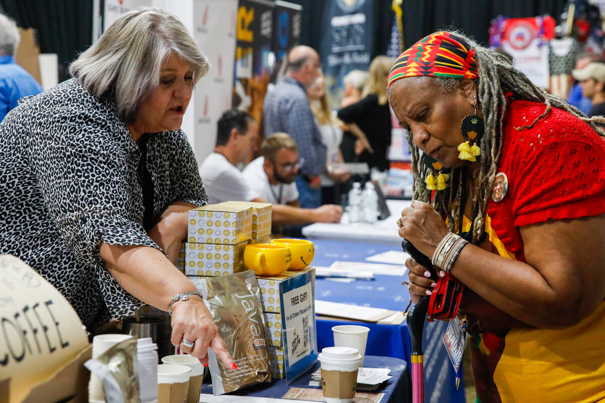 Deb Edwards, left, speaks with Menelika Basele at her coffee booth during the ReAwaken America ...