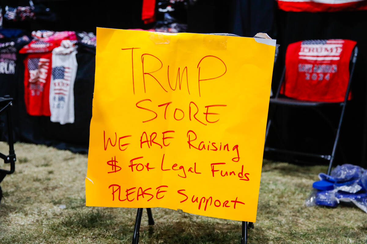 A sign sits at the end of a Trump merchandise table at the ReAwaken America Tour on Friday, Aug ...