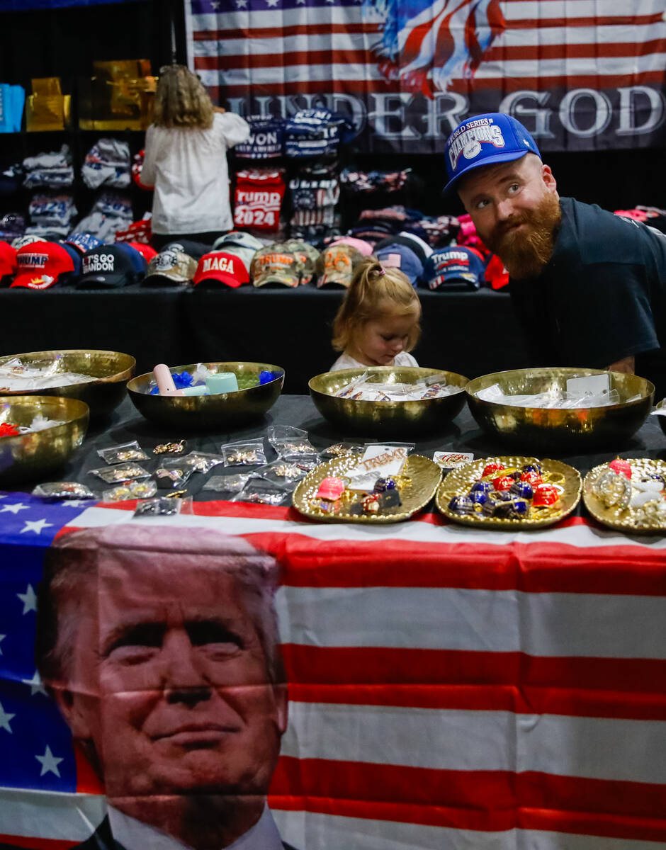 Sam Stafford and his daughter Penelope Stafford, 3, explore the Trump merchandise table at the ...